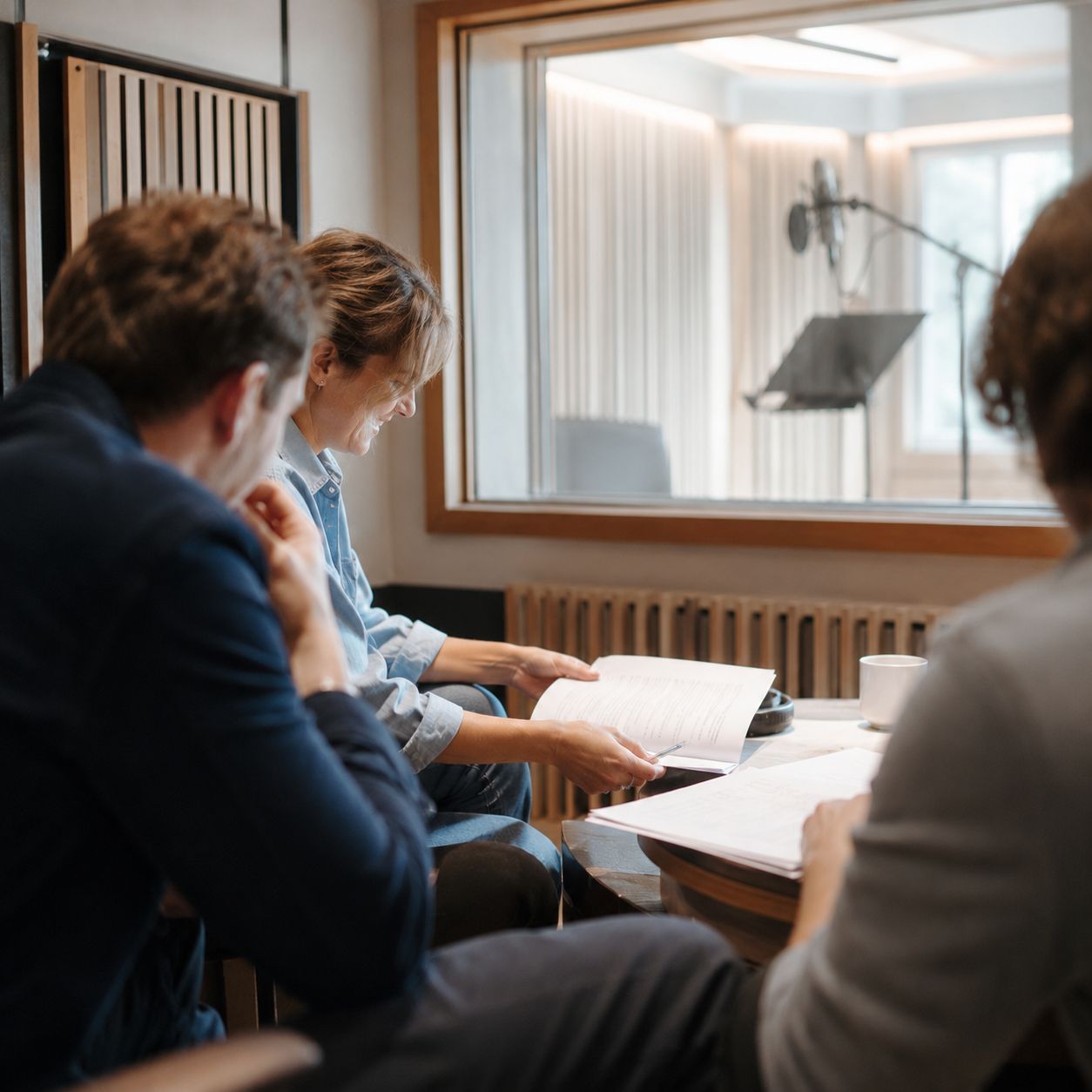 Voice actors and director reviewing pages during a casting conversation.