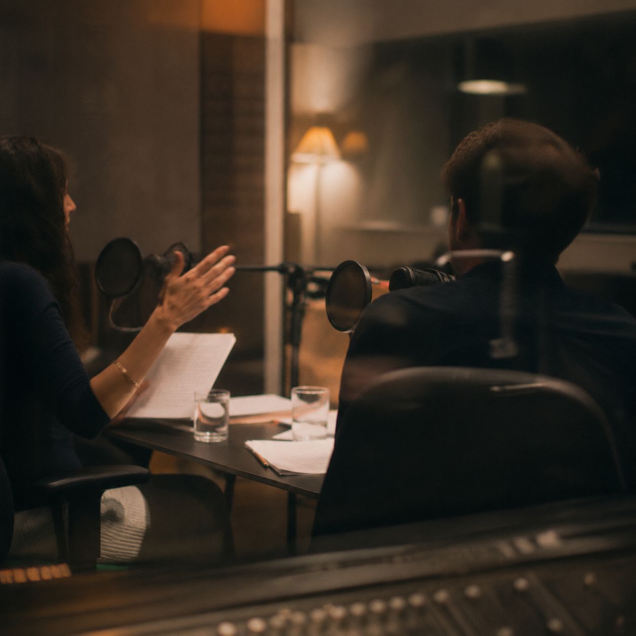 Direction session around a table with script pages, microphones and notes.