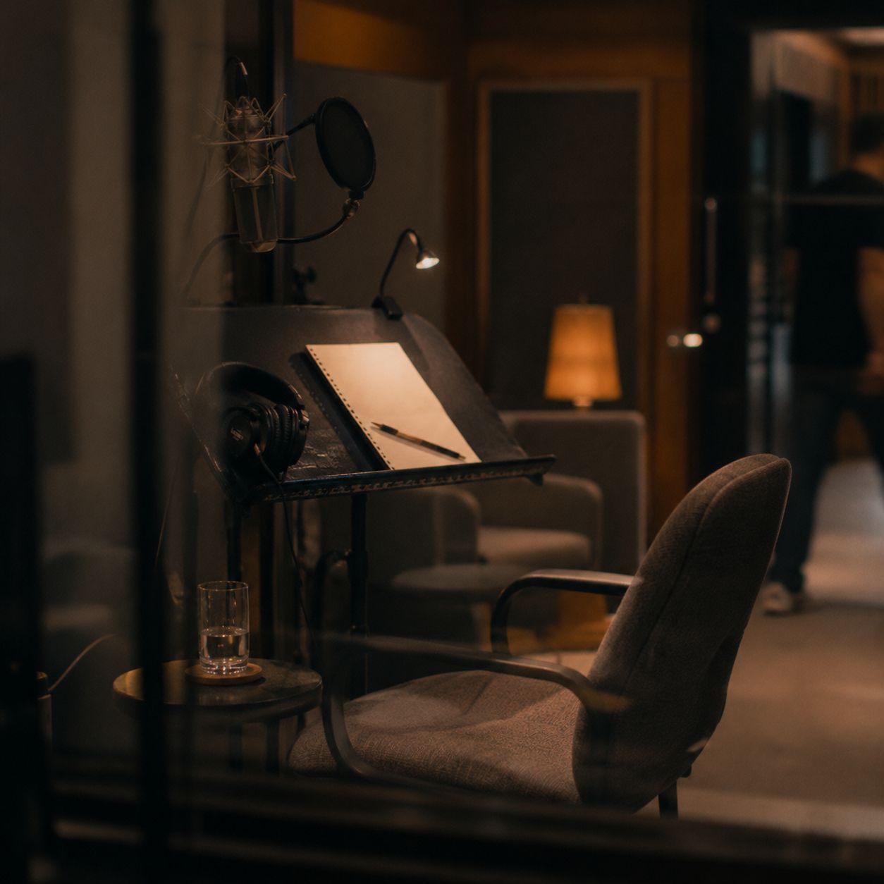 Empty voice booth with microphone, chair and script stand ready for a session.