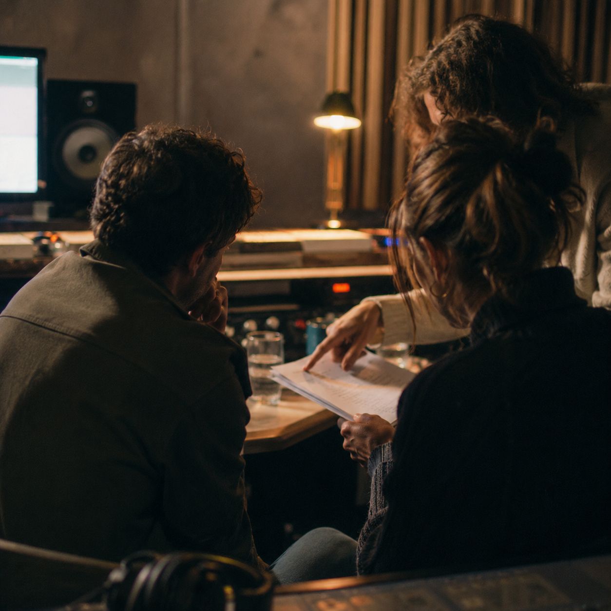 Studio leadership discussion around a desk with printed scripts and note pages.